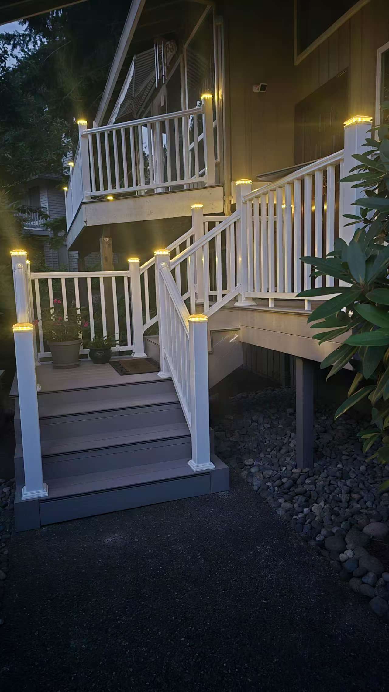 Bothell deck renovation — after, lit composite stairs and white railing at night