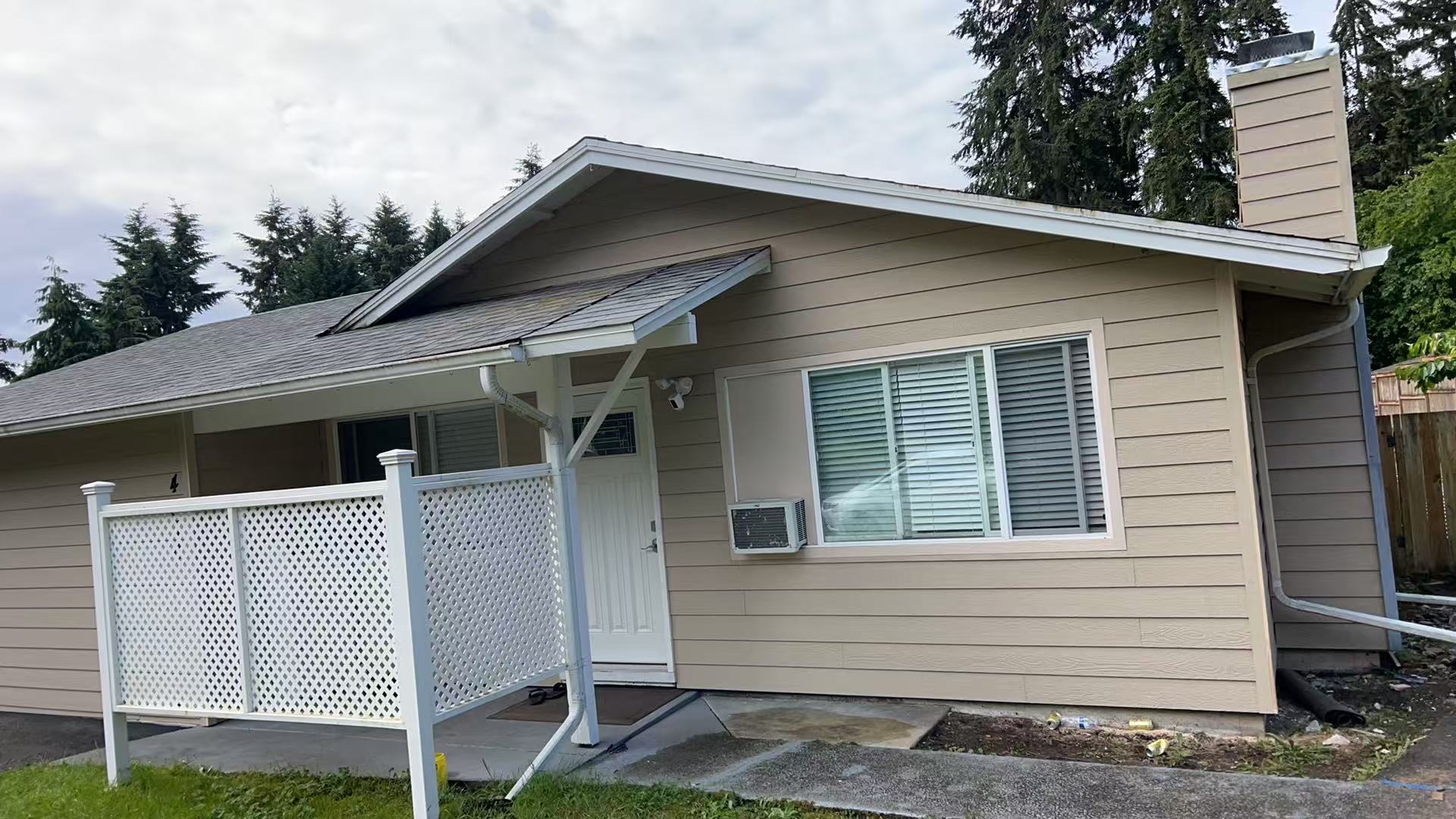 Bothell exterior renovation — after, warm beige siding, crisp white trim, and rebuilt chimney